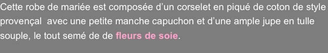 Cette robe de mariée est composée d’un corselet en piqué de coton de style provençal  avec une petite manche capuchon et d’une ample jupe en tulle souple, le tout semé de de fleurs de soie.
 